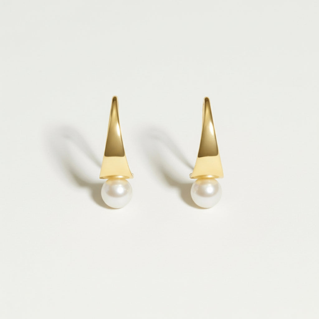Gold earrings with pearl drops on a light gray background