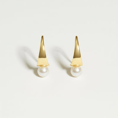 Gold earrings with pearl drops on a light gray background