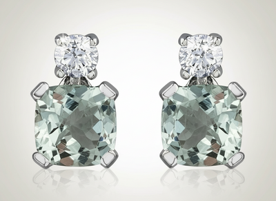 Pair of earrings with green gemstones and silver settings on a white background