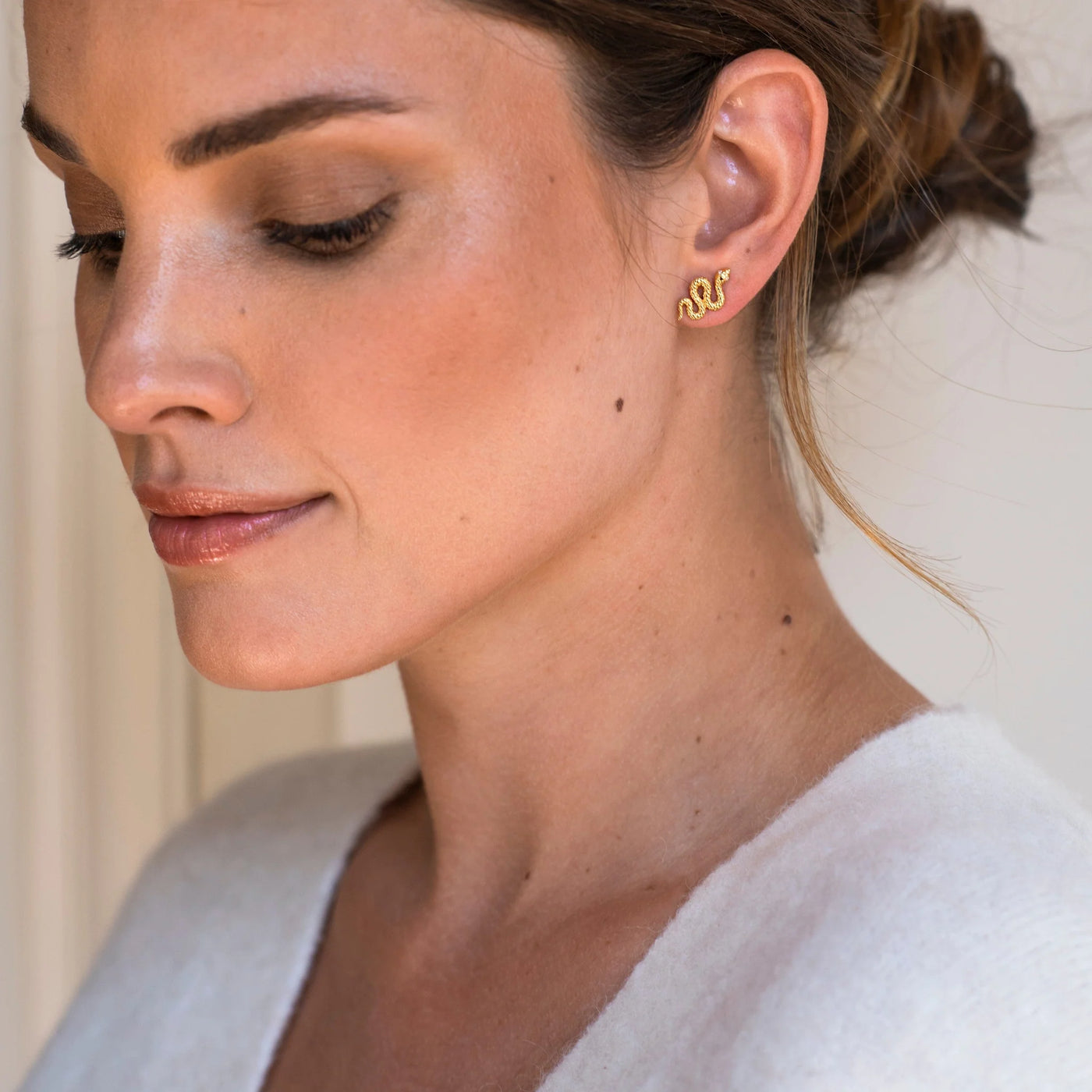 model wearing gold snake stud earrings