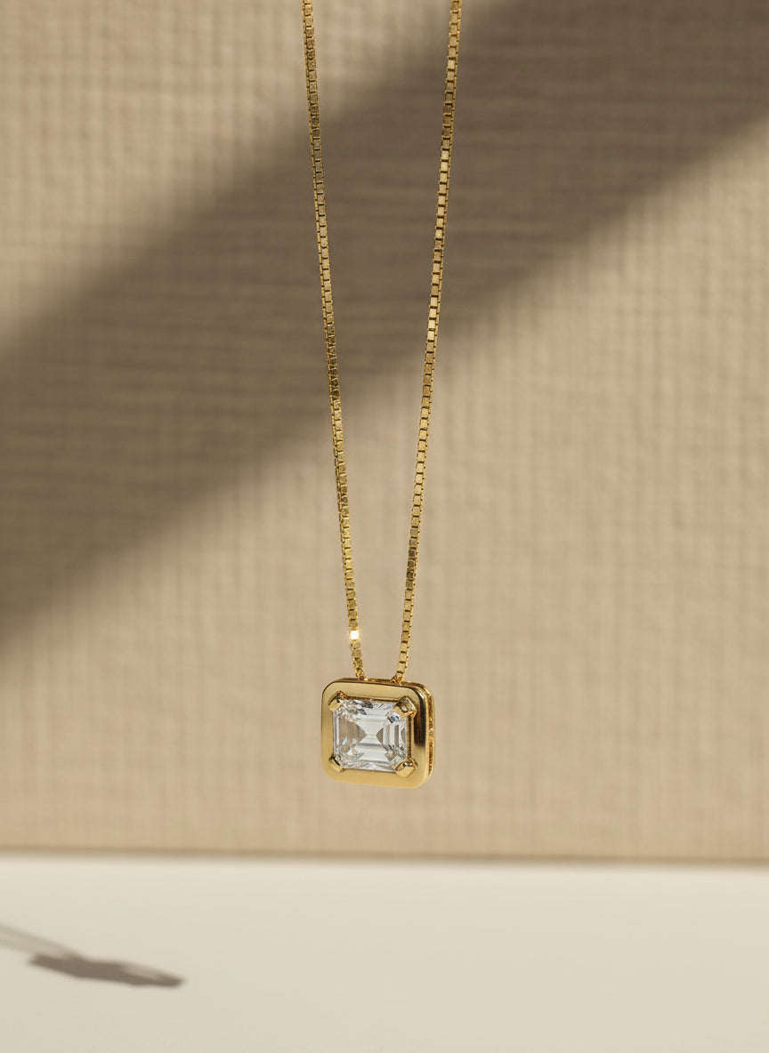 Gold necklace with a rectangular diamond pendant on a light gray background