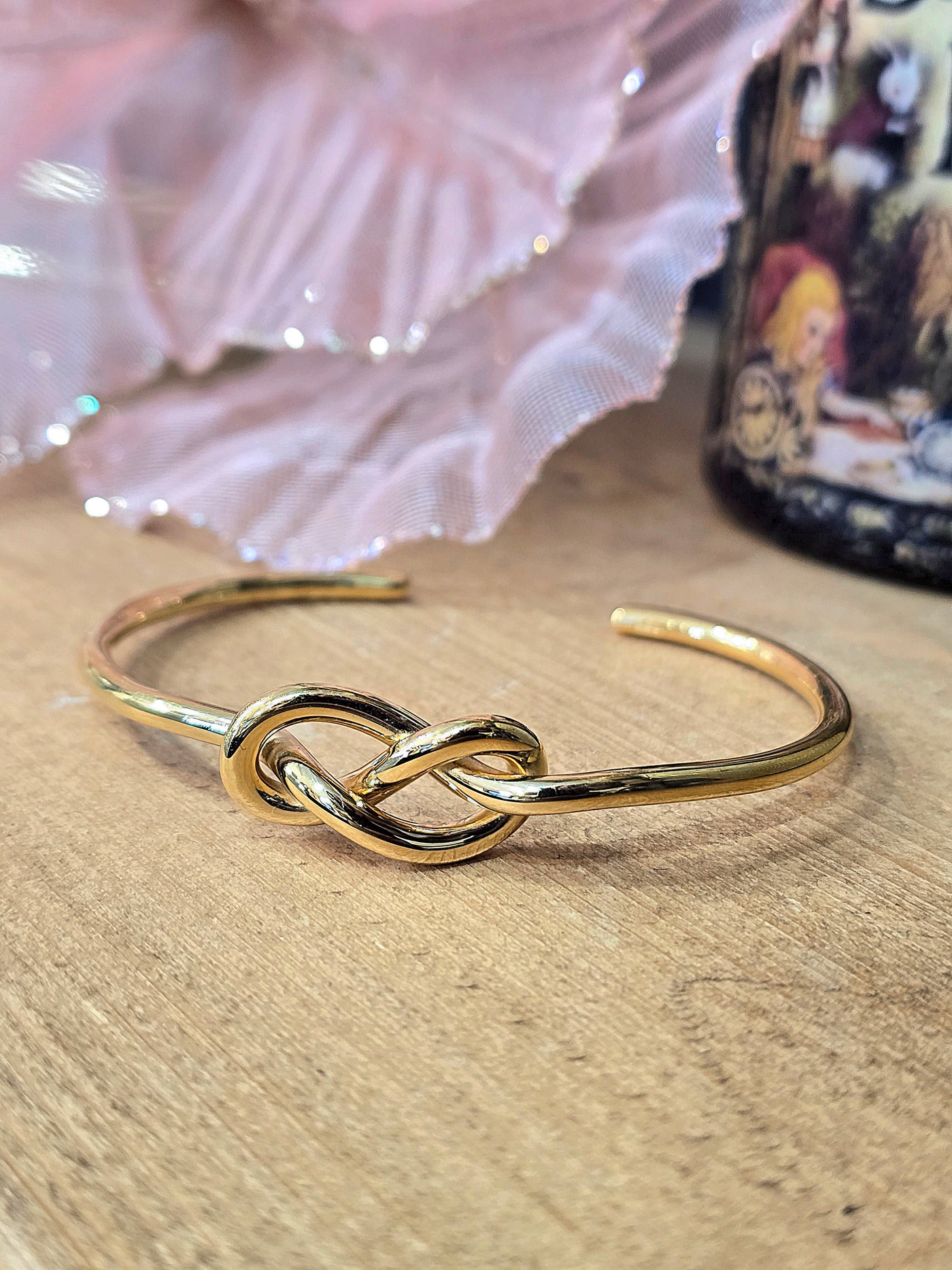 Gold bracelet with a knot design on a wooden surface